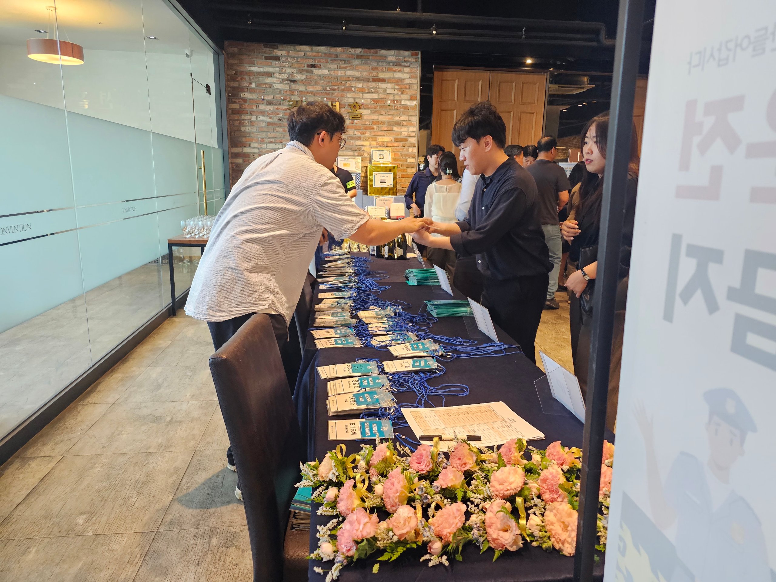 창립기념식 식순 시작 전 접수 데스크에서 참석자 명찰과 안내 자료를 배부하는 모습