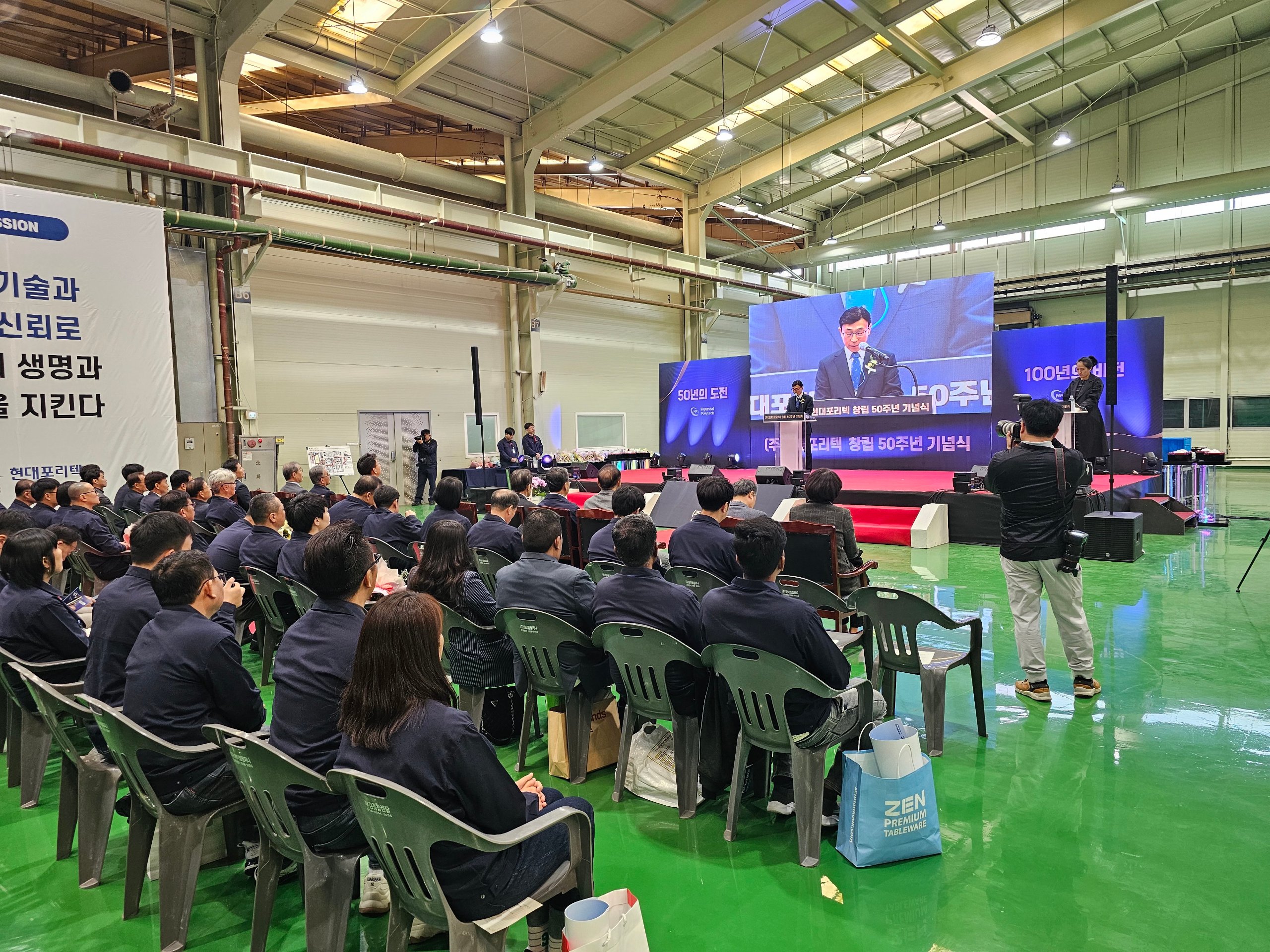 창립기념식 식순 중 기념사 순서에서 대표가 단상에 서고 임직원이 착석해 경청하는 사내 행사장