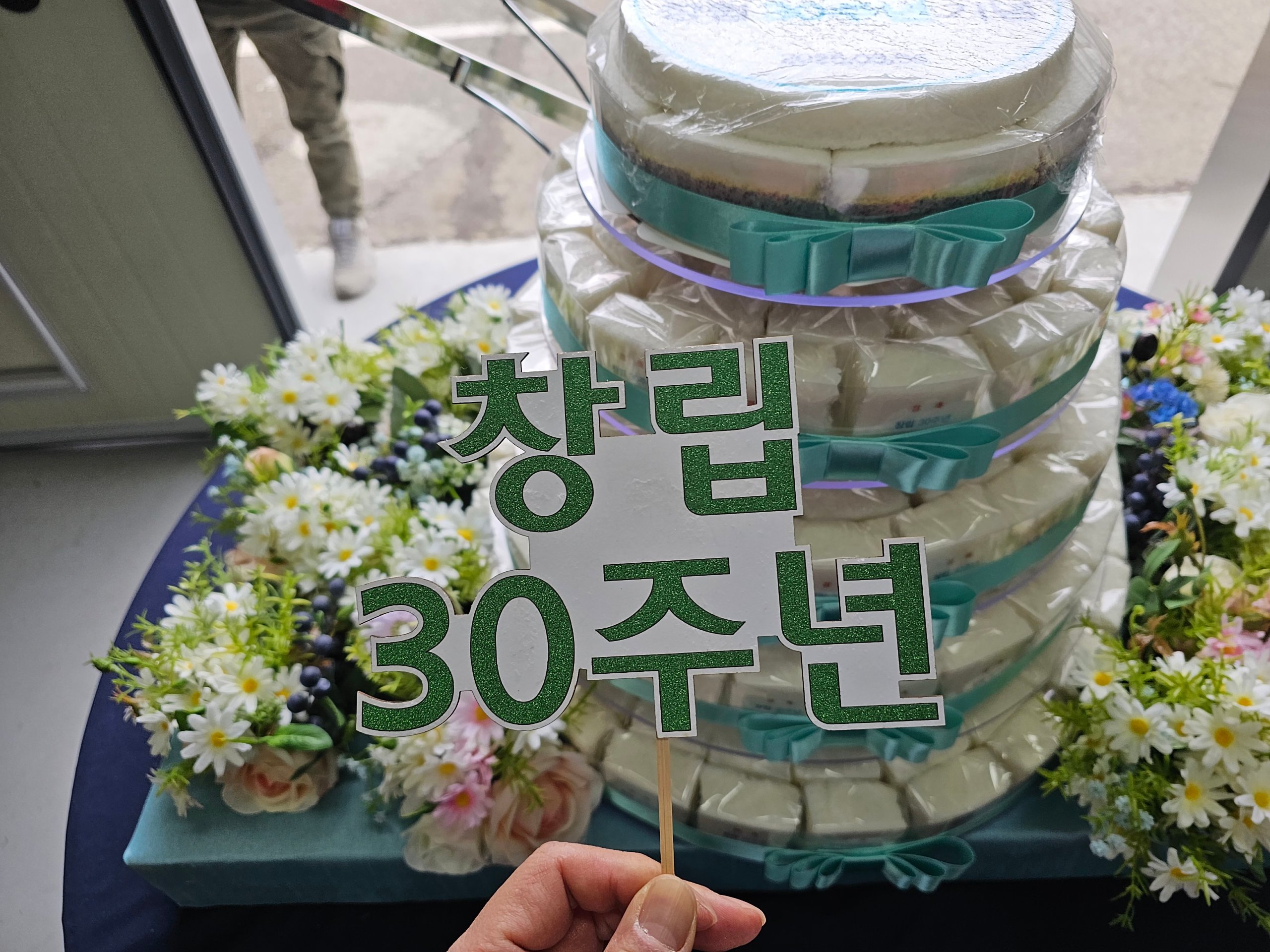 창립기념식 준비물로 마련한 창립 30주년 문구 토퍼를 올린 기념 떡케이크와 꽃 장식